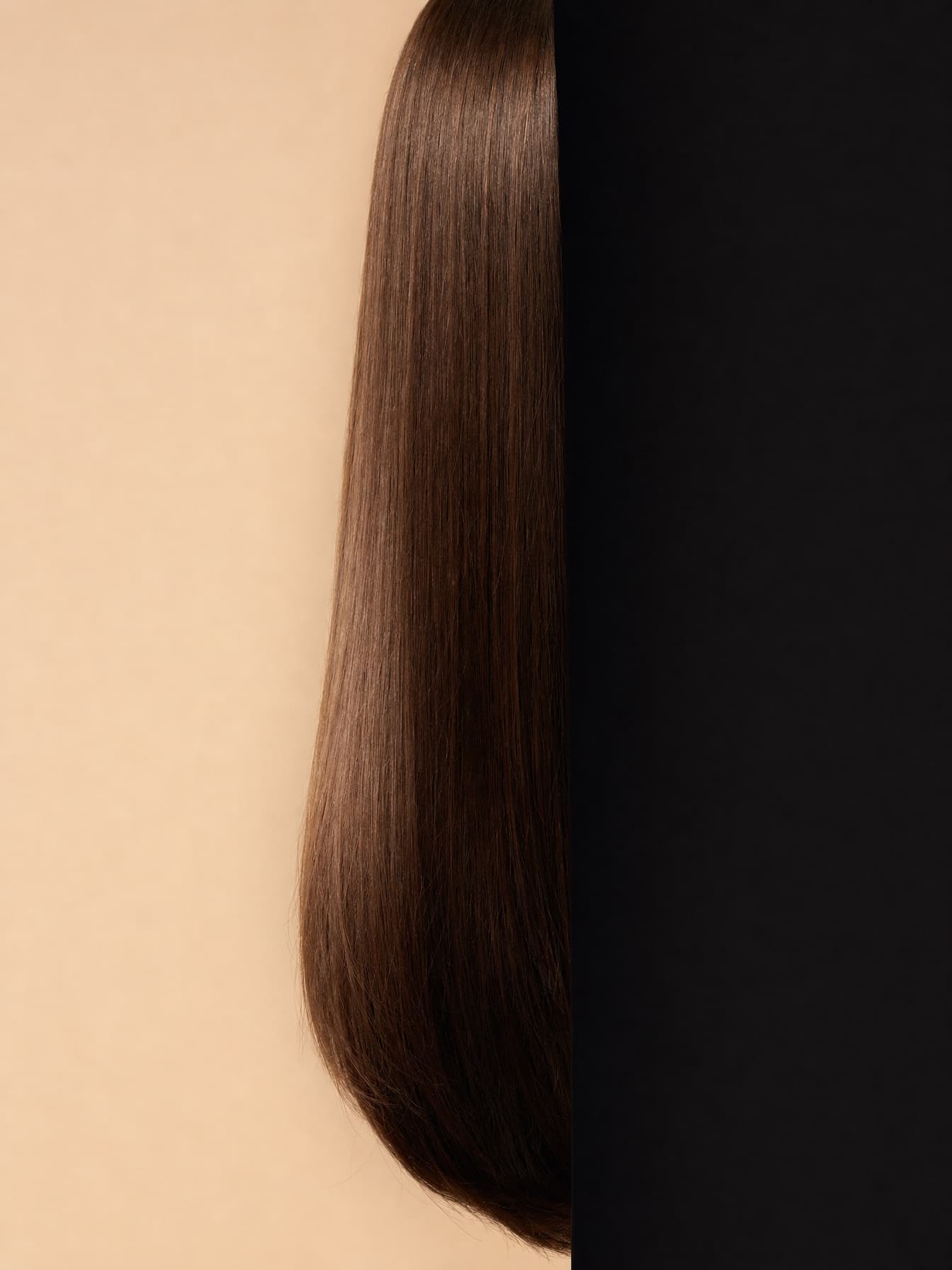 Full length of glossy hair studied as raw material against a split nude and black ground
